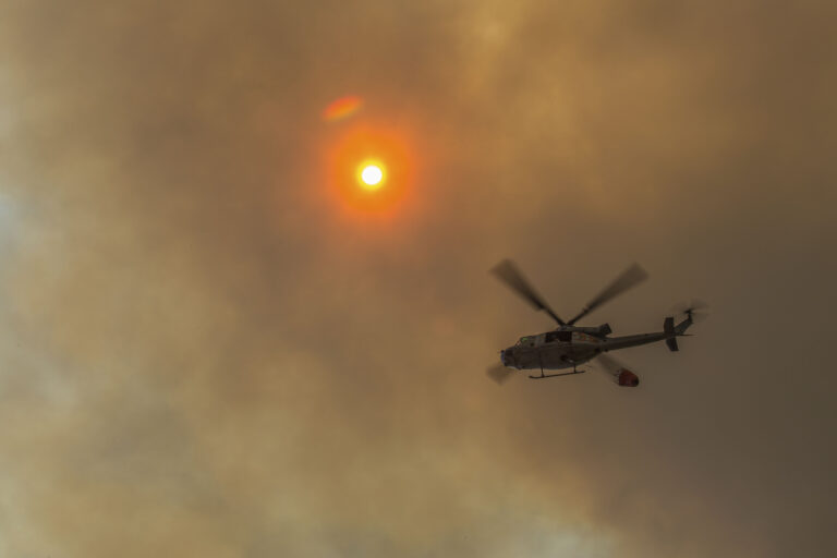 Illustrative file photo: helicopter with water bucket over Camp Pendleton during a wildfire