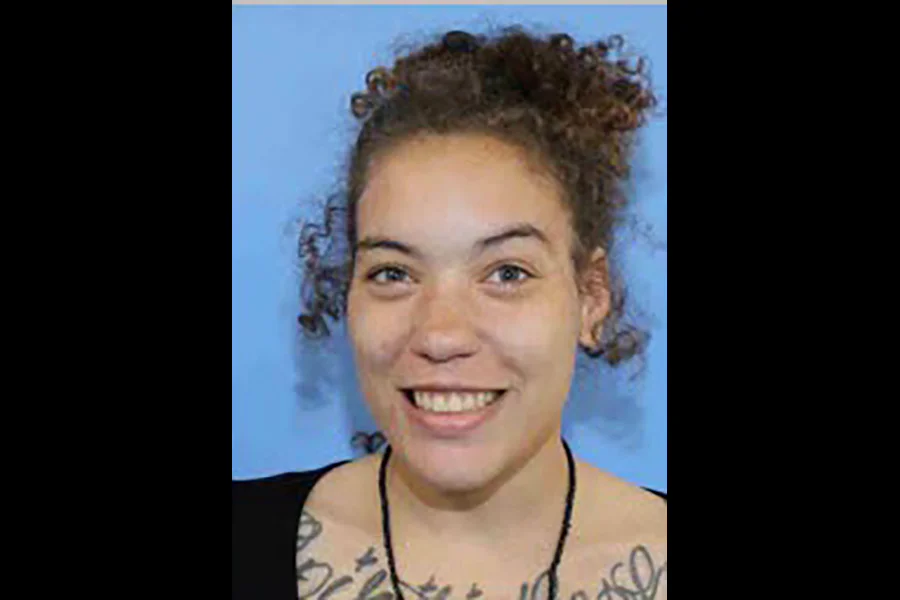 A portrait photograph of thirty-one year old Christina Austin smiling against a clear blue background.